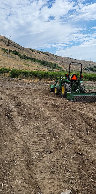 Tractor in an open field facing a hill