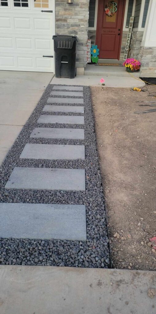 A walkway of dark pebbles with gray paving stones nestled within, leading to the front door of a house