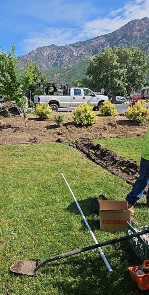 Several yard tools in grassy area lying next to freshly dug trench