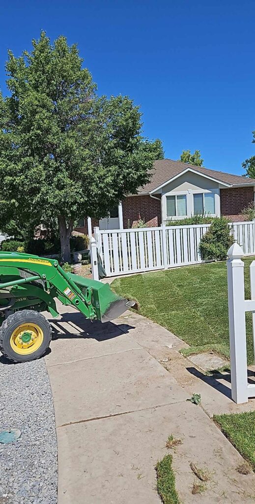 Green tractor entering a grassy area between white fences