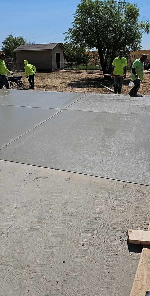 4 workers near freshly laid cement driveway