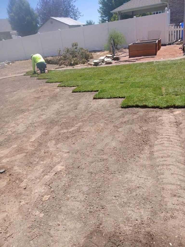 Open field with single worker laying sod in a staircase pattern